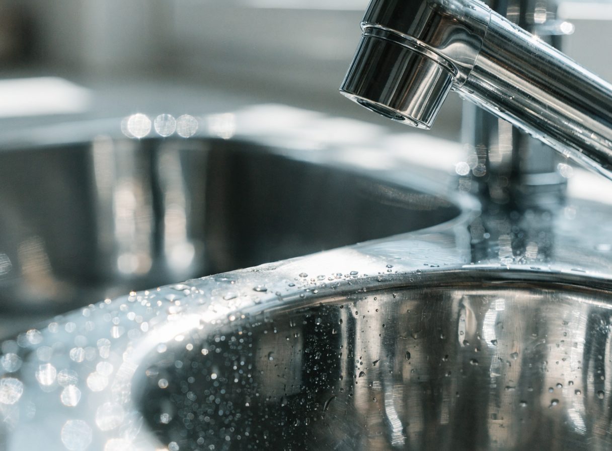 Sparkling clean stainless steel kitchen sink with running water — the Sparkle Clean quality standard